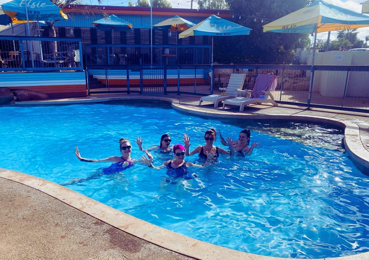 Ladies HQ women waving from the hotel pool